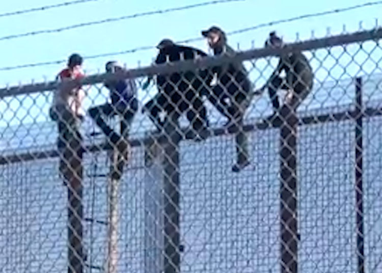 Inmigrantes utilizan una escalera de cuerda para escalar el muro fronterizo en Texas