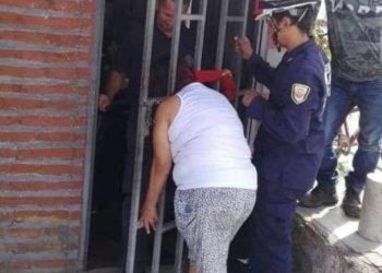 Por fisgona una mujer queda atorada en la reja de una puerta